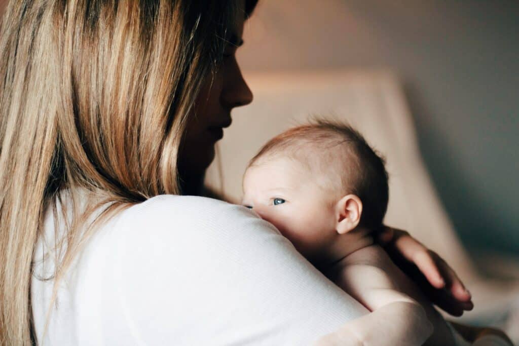 woman in white shirt carrying baby