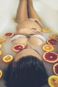 woman in white ceramic bathtub with sliced orange fruits