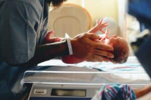 person wearing gray shirt putting baby on scale