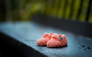 pair of baby's pink knit shoes on bench