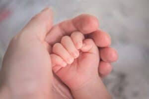 person holding baby's hand in close up photography