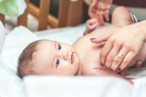 baby lying in white textile