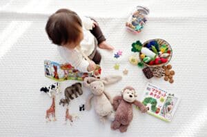 boy sitting on white cloth surrounded by toys